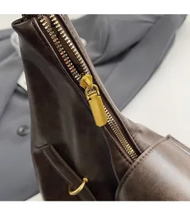 Detail of smooth golden metal zipper and dark brown leather texture of the tote bag