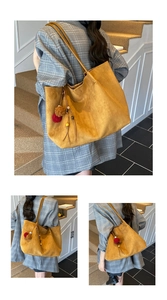 Detail of a large mustard yellow faux suede tote bag with decorative plush charms