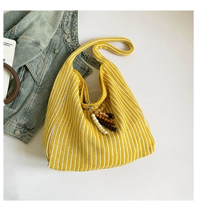 Detail of yellow and white striped knit tote bag with colorful beaded charm accessory