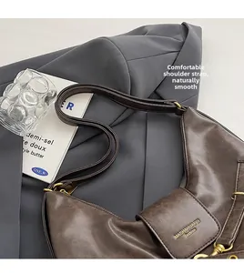 Detail of dark brown leather tote with gold logo on a grey blazer and book