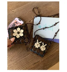 Détail du sac bohème en coque de noix de coco avec fleur en bois et bandoulière perlée