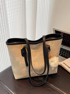 Minimalist beige tote bag with black straps and plush charm for work or school
