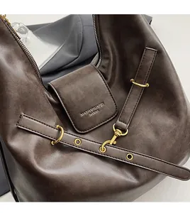Detail of dark brown leather hobo bag with vintage gold hardware and brand logo