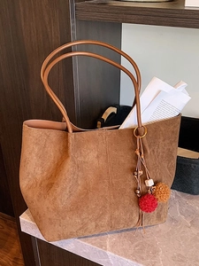 Brown large capacity suede tote bag with decorative tassel on marble surface