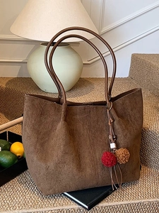 Brown suede tote bag with minimalist design and decorative pompom for daily commuting
