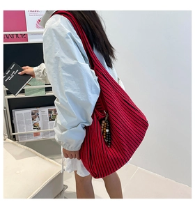 Detail of red and black striped knit tote bag with colorful beaded charm accessory