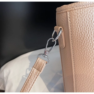Details einer beigen Tasche aus genarbtem Leder mit poliertem silbernem Karabinerhaken