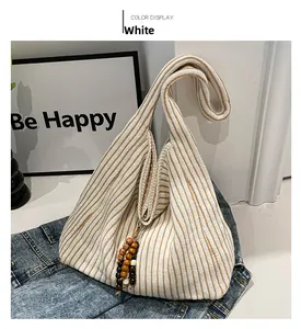 Detailed macro view of striped knit tote bag fabric with wooden bead tassel accessory
