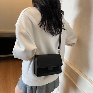 Borsa a tracolla quadrata minimalista in pelle nera con tracolla regolabile indossata