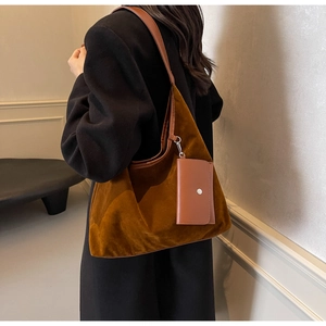 Detailed texture of brown suede tote bag with leather straps on a black wool coat