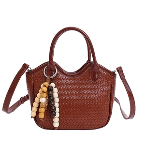 Dark brown woven bucket bag with beaded charm and adjustable strap on white background