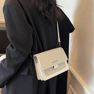 Piccola borsa a tracolla bicolore con cinturino largo indossata da una modella in blazer