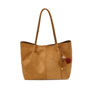 Brown suede tote bag with leather shoulder straps and decorative plush charm on white background