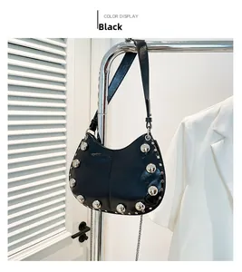 Close-up of black rivet handbag showing large silver metal studs and polished texture