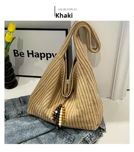 Detail of khaki striped knit tote bag with a colorful beaded charm and soft texture