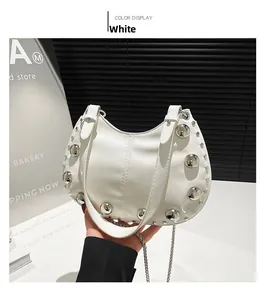 Detail of white half-moon saddle bag with silver studs and metal chain strap