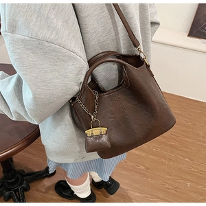 Detail of dark brown matte leather bucket bag with a mini pouch and metal chain