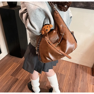Macro detail of caramel tote bag featuring textured PU leather and a cute brown bear charm