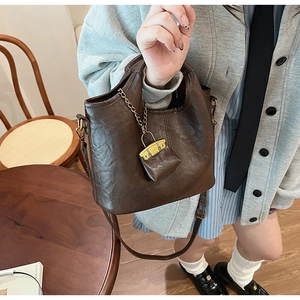 Detailed view of deep brown bucket bag with vintage leather texture and chain charm