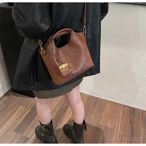 Brown vintage bucket bag detail with adjustable shoulder strap and gold lock pendant