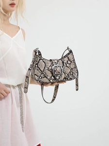 Y2K style snake print shell bag with silver buckle and rivets on white studio background