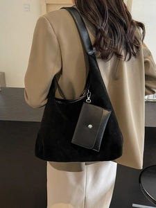 Minimalist black suede tote bag with mini pouch shown on a stylish model in karki suit