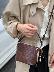 Deep brown woven bucket bag with drawstring liner and beaded accent on a model