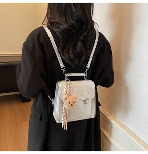 Silver glitter mini backpack shown on model with teddy charm and adjustable straps