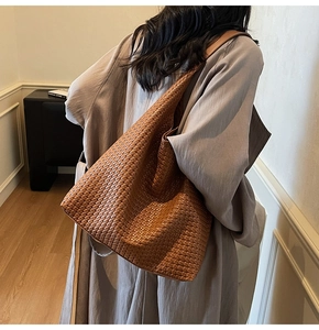 Detailed texture of caramel brown woven leather hobo tote bag worn by a model