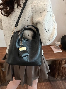 Retro black leather bucket bag with mini pouch shown on a model in knitwear