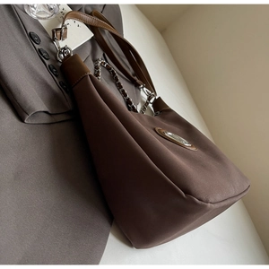 Detail of dark brown hobo bag with metal logo, leather strap and woven chain detail