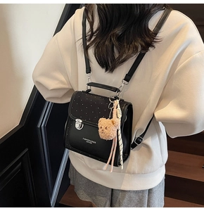Detail of black backpack with polka dot flap, silver metal lock, and plush bear charm