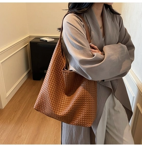 Detailed close-up of warm brown hand-woven leather tote bag texture and hobo style