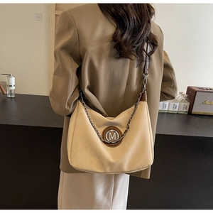 Detail showing beige hobo bag with M logo and chain strap on a brown suit model