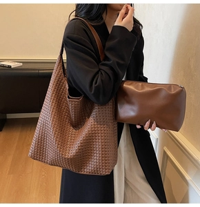 Detailed view of brown woven tote bag set with matching zipper clutch on model shoulder