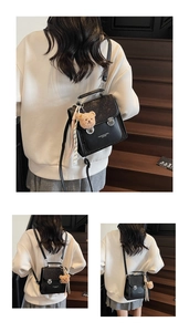 Close-up of black PU leather backpack with metal ring buckle and bear charm detail