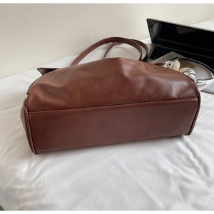 Detailed view of the brown leather tote bag with reinforced base stitching and shoulder strap