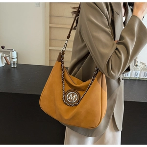 Detail of hobo bag with gold metal M logo and chain decoration in ginger yellow suede
