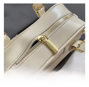 Detail of golden zipper and hardware on cream white fashion pillow bag with brand logo