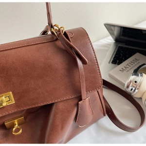 Detail of vintage brown leather tote bag with golden twist lock and textured finish