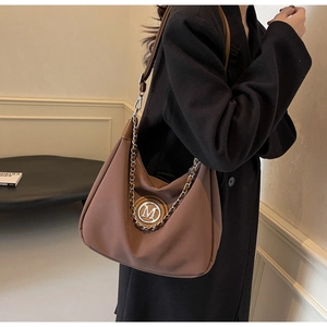 Detail of dark brown leather shoulder bag with gold M-logo and decorative chain link