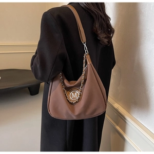 Detail of brown fabric hobo bag with M-logo hardware and leather chain strap on model