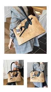 Detail van bruine suède tote bag met een pluche beer hanger en zwarte handvaten
