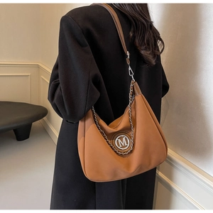 Detail of brown nylon hobo bag with silver chain and M logo pendant on adjustable strap