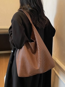 Brown woven leather tote bag for women showing spacious shoulder carry style on a model