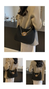 Detail view of the black canvas shoulder bag with brown leather trim and chain strap