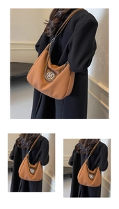 Close-up of caramel hobo bag featuring silver M logo and metal chain detail