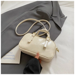 Detailed top view of cream leather boston bag with gold hardware on professional styling