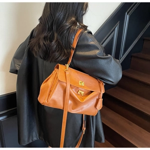 Detail of caramel brown faux leather bag featuring a gold twist lock and pleated side design