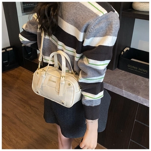 Rear view of cream Boston bag worn crossbody by a model for a stylish daily look
